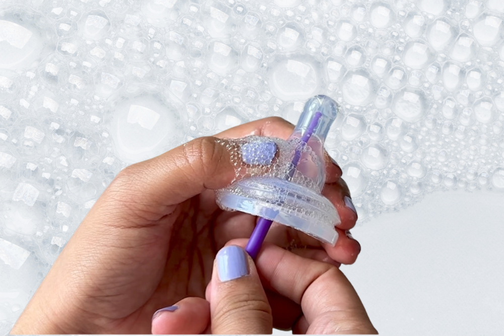 parent cleaning mōmi baby bottle nipple with cleaning tool in soapy water | mōmi